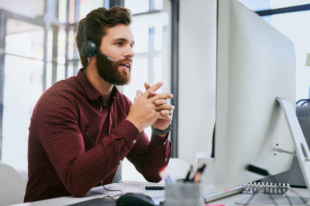 A male customer support agent assisting customers at his desk